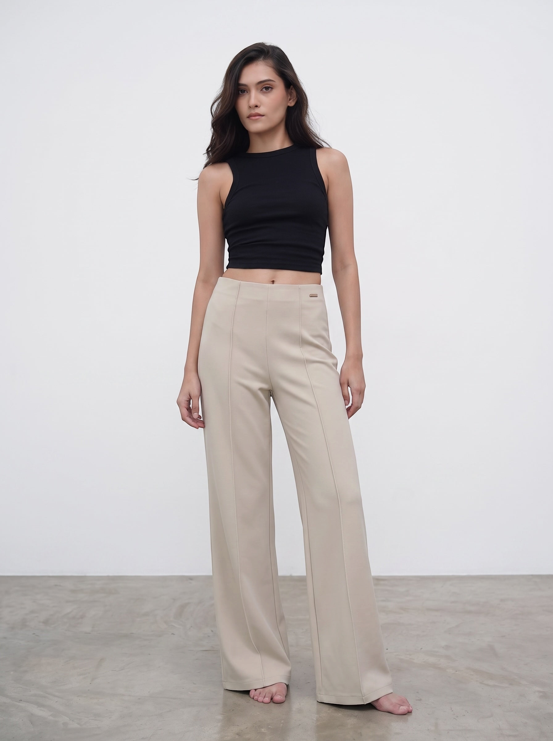 Model wearing duwies beige high-waisted wide-leg tailored trousers with front seam detail and a black sleeveless top.